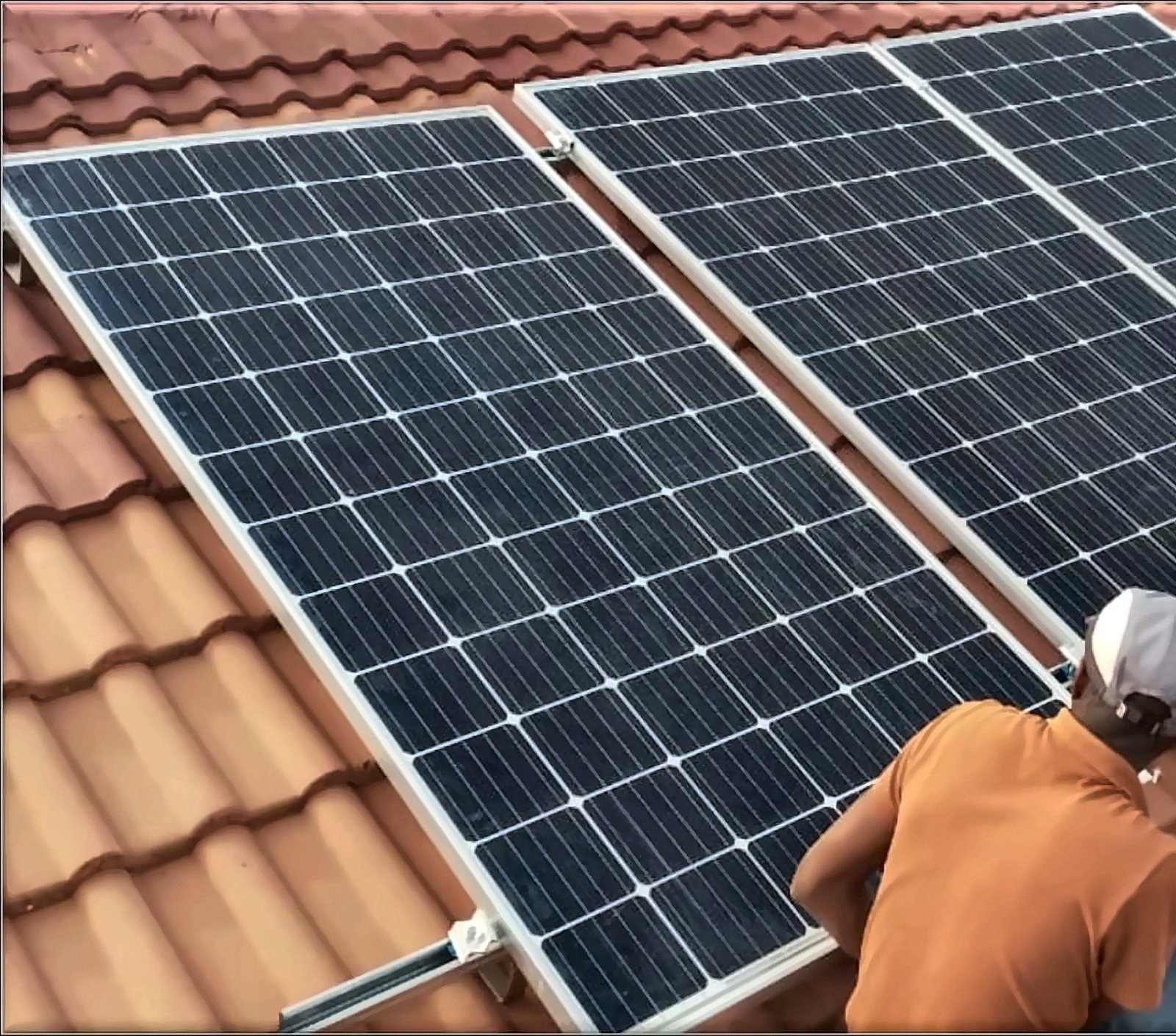 Technician mounting solar panels on a tiled roof